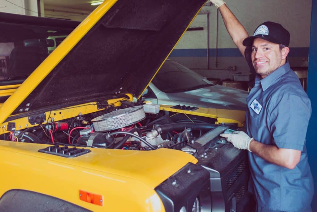 Car technician working in engine bay of car