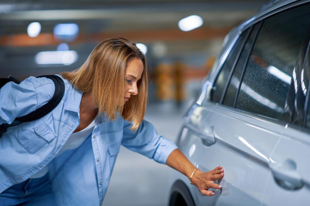 woman looking at car door dent