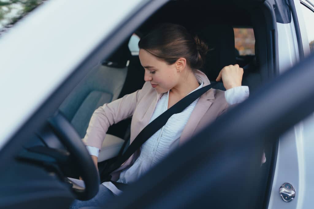 woman putting seat belt on to ensure seat belt safety