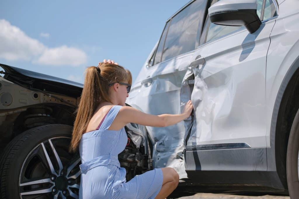 woman looking at car in need of collision repairs