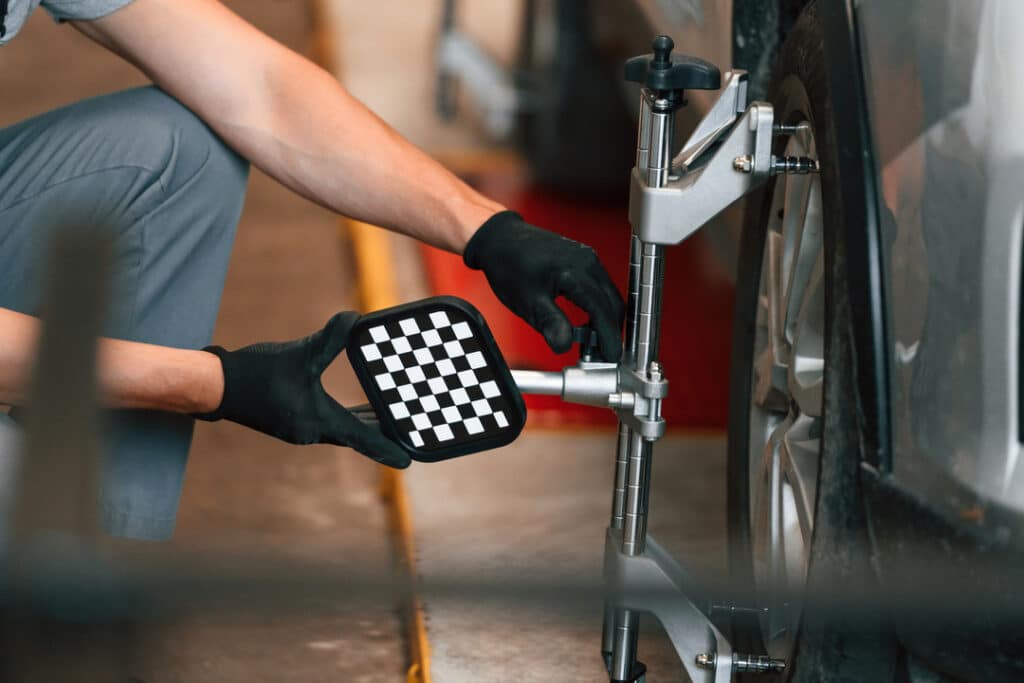 Professional adjusts wheel alignment on car