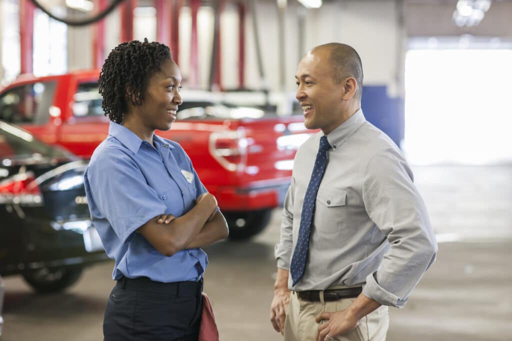 Two certified auto repair technicians talking in the shop