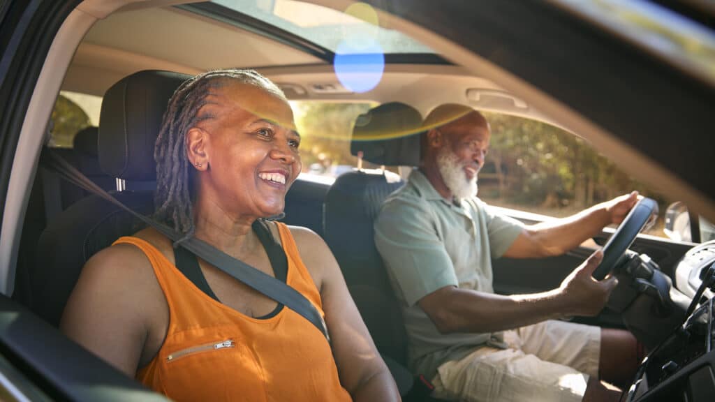 A senior couple out driving an older car